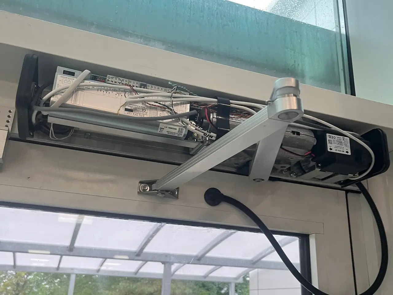 Automatic swing door operator, arm and header above a glazed entrance