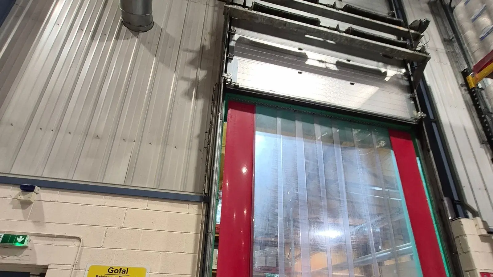 High-speed roll-up door with a red frame and clear strips in a warehouse